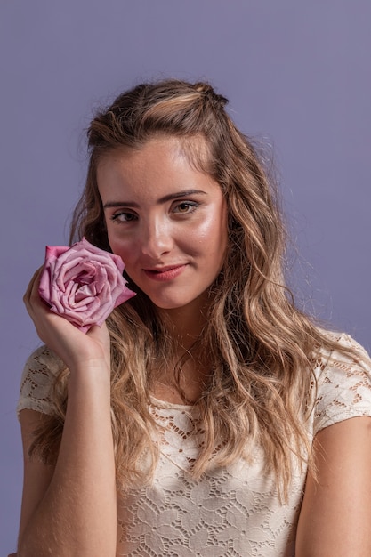 Foto gratuita vista frontal de la mujer posando mientras sonríe y sostiene una rosa