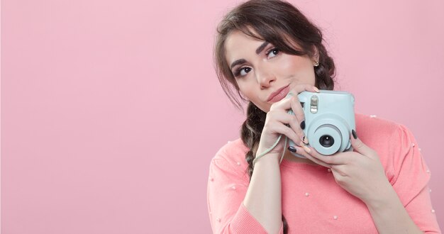 Vista frontal de la mujer posando mientras sostiene una cámara