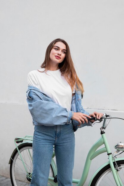 Vista frontal de la mujer posando mientras sostiene su bicicleta