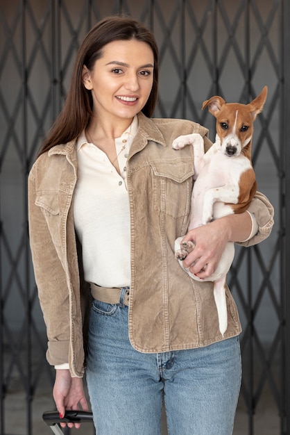 Vista frontal de la mujer posando mientras sostiene a su perro en brazos