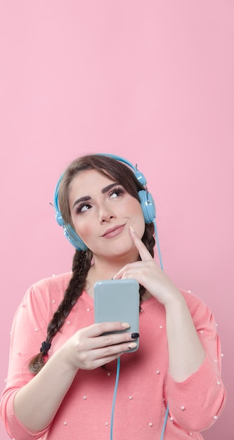 Vista frontal de la mujer posando mientras sostiene el teléfono y el dedo como si estuviera pensando