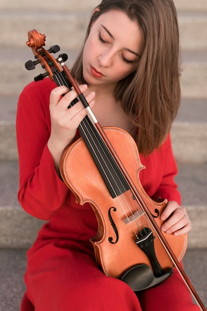 Vista frontal de la mujer posando mientras sostiene el violín