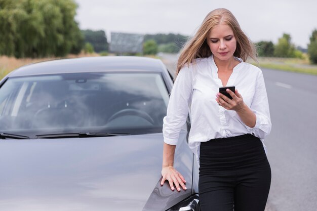 Vista frontal de la mujer que controla el teléfono