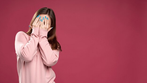 Vista frontal de la mujer que cubre su rostro con las manos