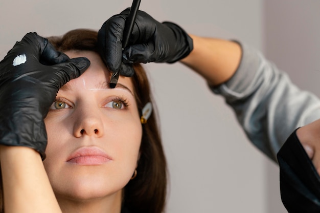 Vista frontal de la mujer recibiendo un tratamiento de cejas de esteticista