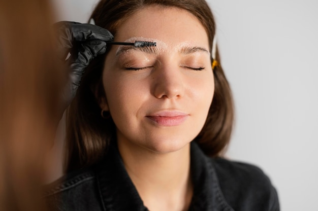Vista frontal de la mujer recibiendo un tratamiento de cejas