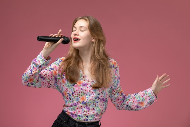 Vista frontal mujer rubia cantando con su micrófono