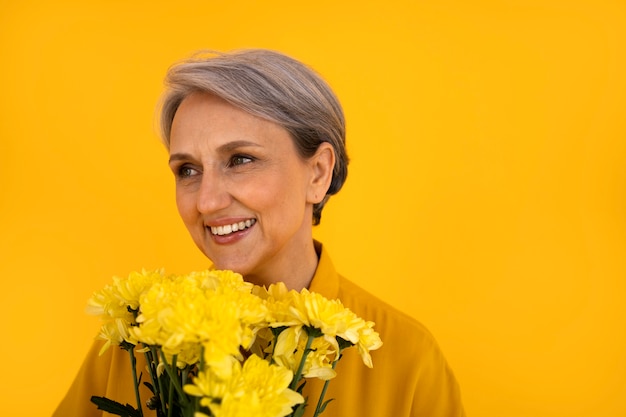 Foto gratuita vista frontal mujer senior posando con flores