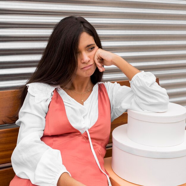 Vista frontal de la mujer sentada en un banco con cajas