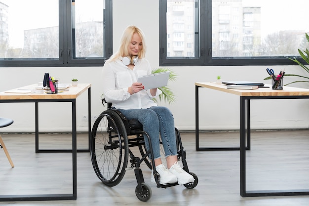 Foto gratuita vista frontal de la mujer en silla de ruedas en la oficina