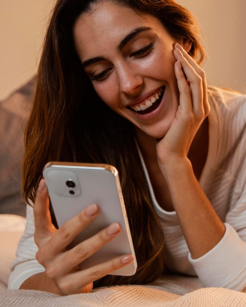 Vista frontal de la mujer con smartphone en casa