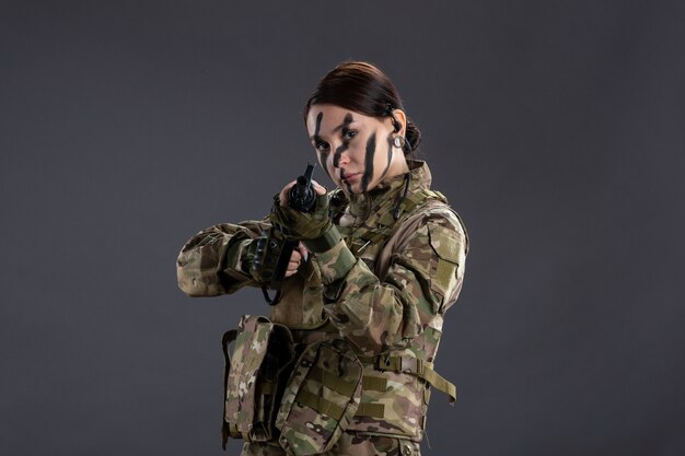 Vista frontal mujer soldado en camuflaje con ametralladora en el escritorio oscuro tanque guerra israel