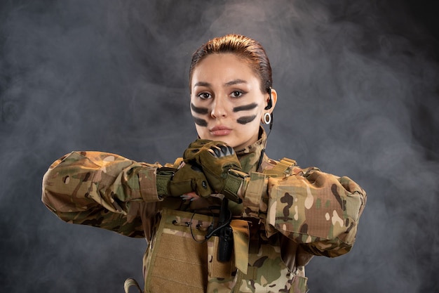 Foto gratuita vista frontal de la mujer soldado en camuflaje en la pared oscura