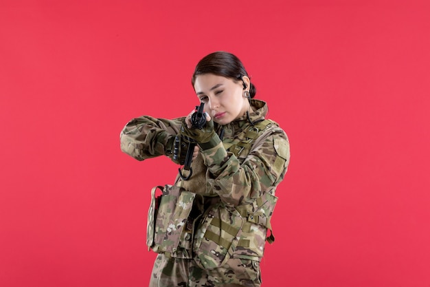 Foto gratuita vista frontal mujer soldado en camuflaje con pared roja de ametralladora