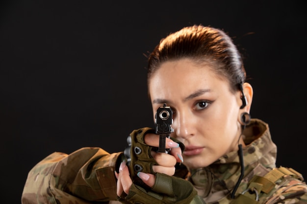 Foto gratuita vista frontal de la mujer soldado con pistola en uniforme sobre pared negra