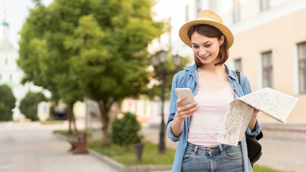 Vista frontal mujer con sombrero comprobando teléfono móvil