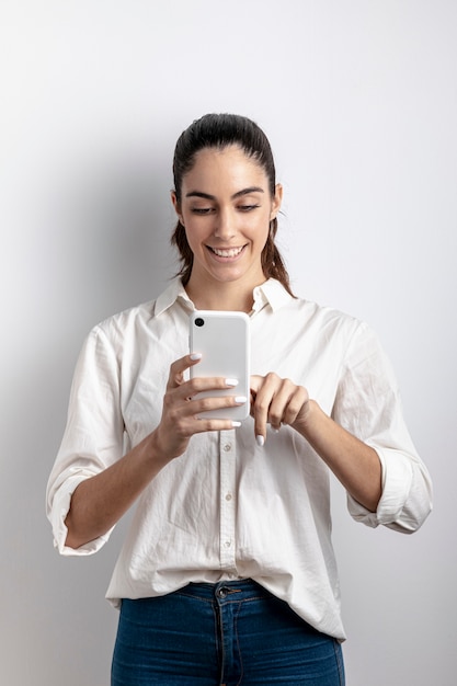 Foto gratuita vista frontal de la mujer sonriendo y sosteniendo el teléfono inteligente