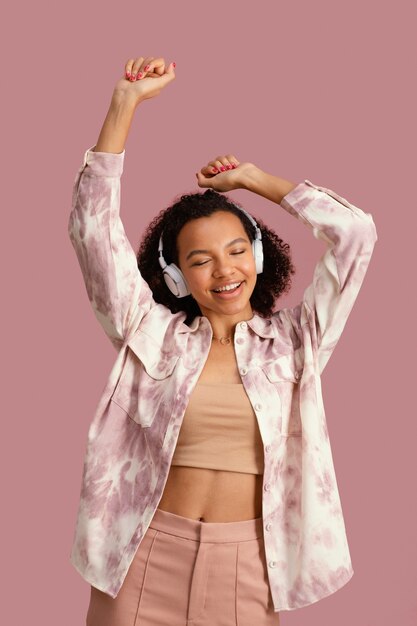 Vista frontal de la mujer sonriente con auriculares bailando con música