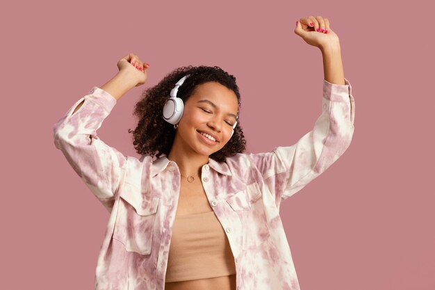 Vista frontal de la mujer sonriente con auriculares bailando