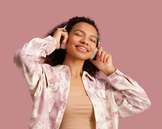 Vista frontal de la mujer sonriente con auriculares escuchando música