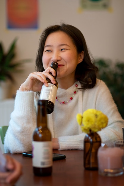 Vista frontal de una mujer sonriente con una botella de kombucha