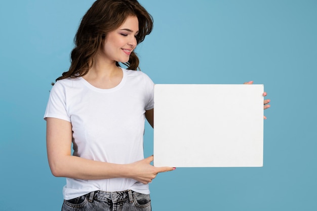 Vista frontal de la mujer sonriente con cartel en blanco