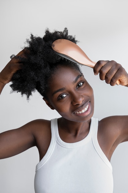 Vista frontal mujer sonriente cepillando el cabello