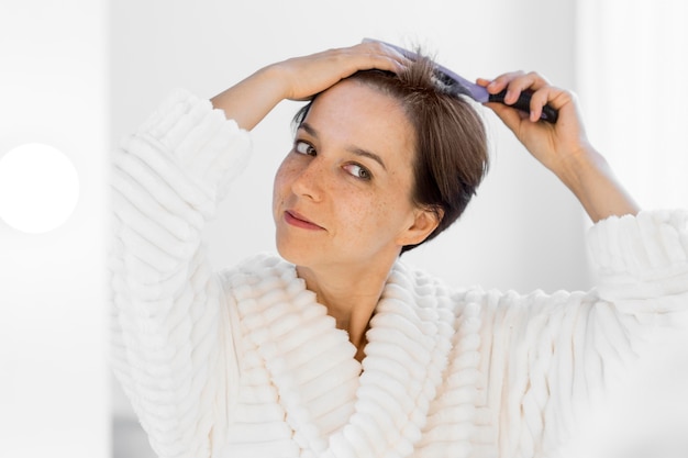 Vista frontal mujer sonriente cepillando su cabello