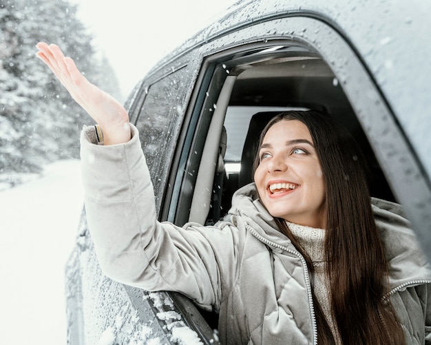 Vista frontal de la mujer sonriente en el coche durante un viaje por carretera