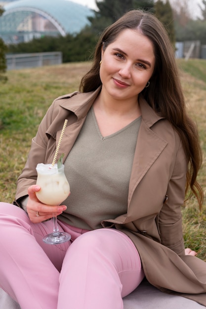 Foto gratuita vista frontal mujer sonriente con cóctel al aire libre