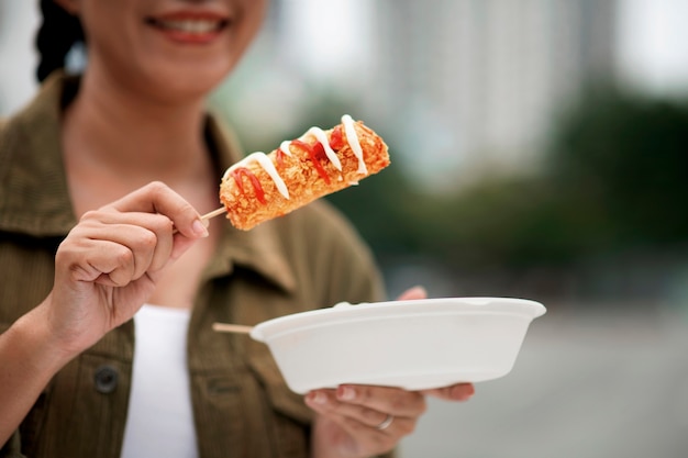 Foto gratuita vista frontal de mujer sonriente comiendo corn dog