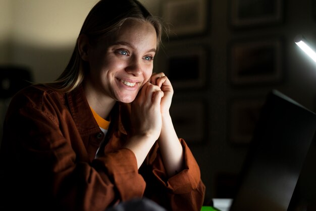 Vista frontal de la mujer sonriente en la computadora portátil