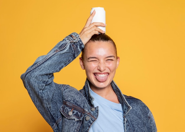 Vista frontal de la mujer sonriente con lata de refresco en la cabeza