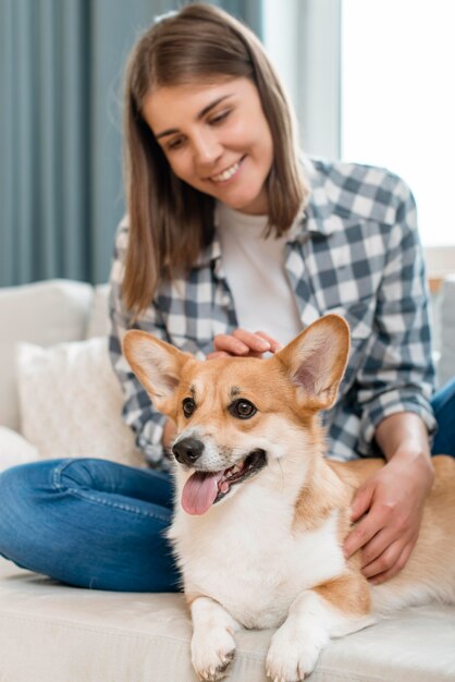 Vista frontal de la mujer sonriente con lindo perro en el sofá