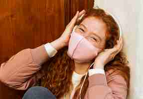 Foto gratuita vista frontal de la mujer sonriente con mascarilla al aire libre y auriculares