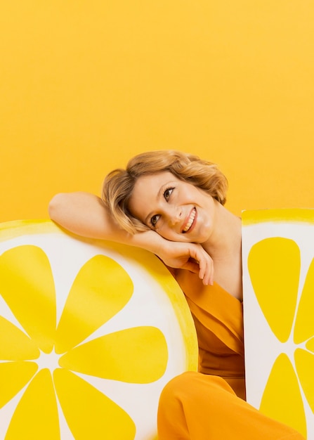 Vista frontal de la mujer sonriente posando con decoraciones de rodajas de limón