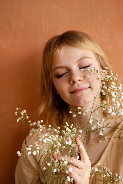 Vista frontal de la mujer sonriente posando con flores