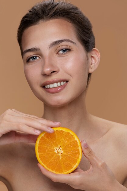 Vista frontal mujer sonriente posando con naranja