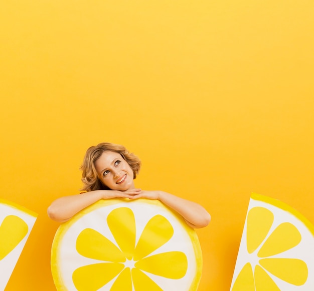 Vista frontal de la mujer sonriente posando con rodajas de limón decoración y copia espacio