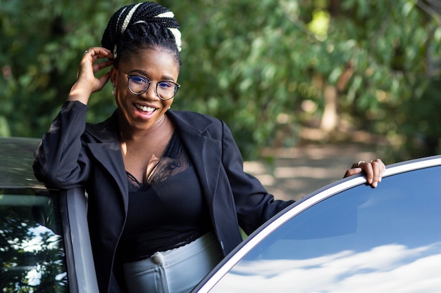 Vista frontal de la mujer sonriente posando con su coche nuevo