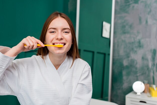 Vista frontal de la mujer sonriente que se cepilla los dientes