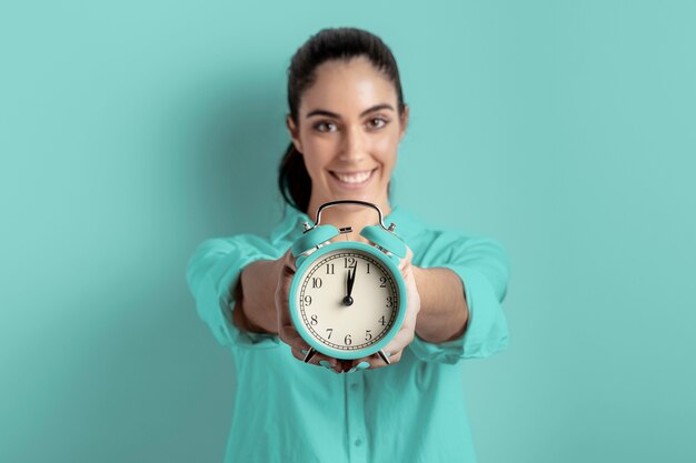 Vista frontal de la mujer sonriente que sostiene el reloj