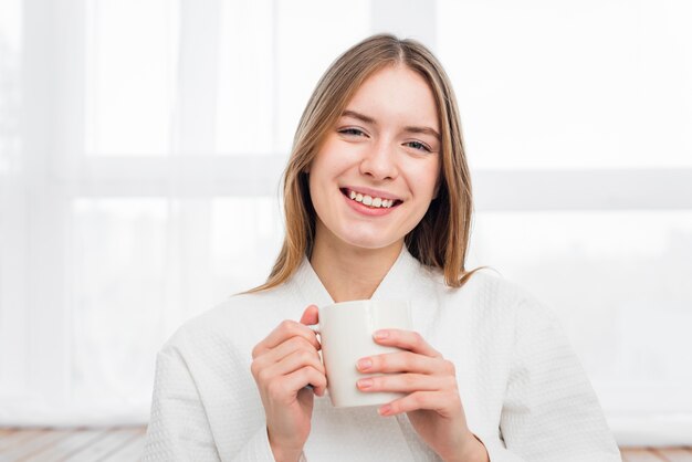 Vista frontal de la mujer sonriente que sostiene la taza