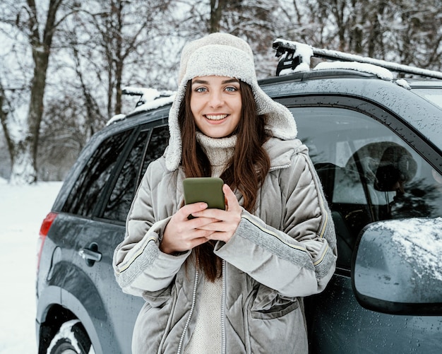 Vista frontal de la mujer sonriente con smartphone durante un viaje por carretera