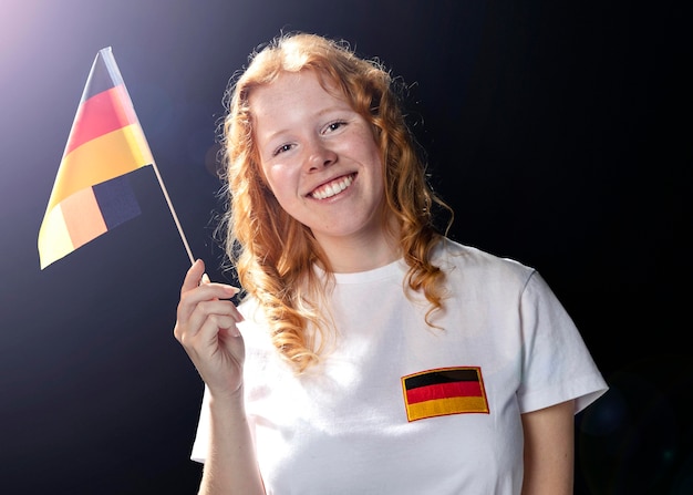 Foto gratuita vista frontal de la mujer sonriente sosteniendo la bandera alemana