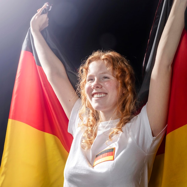 Vista frontal de la mujer sonriente sosteniendo la bandera alemana