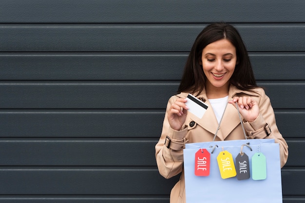 Foto gratuita vista frontal de la mujer sonriente sosteniendo bolsas de la compra con etiquetas y espacio de copia