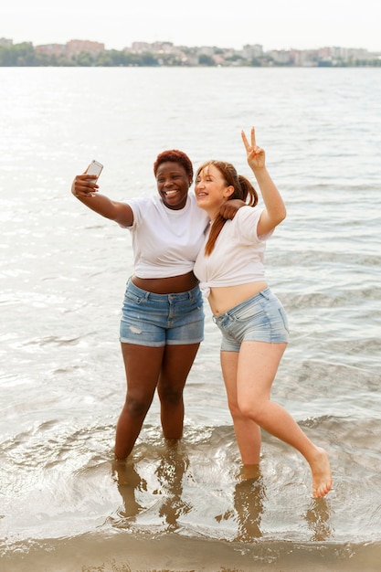 Vista frontal de la mujer sonriente tomando selfie en la playa.