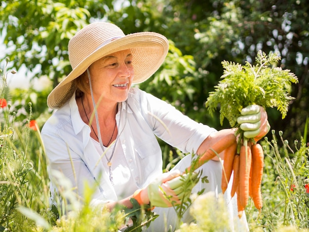 Vista frontal mujer sosteniendo algunas zanahorias frescas en su mano