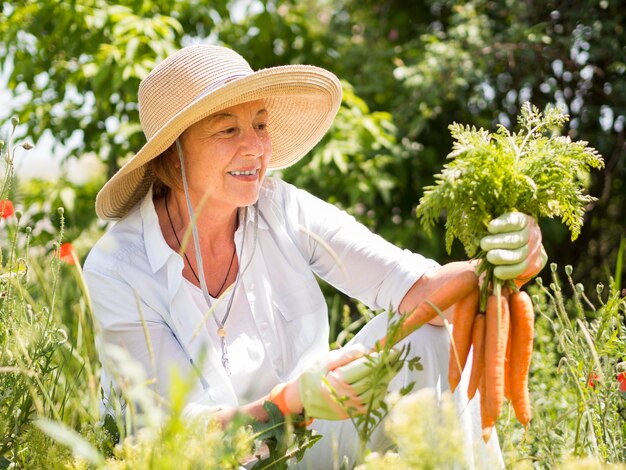 Vista frontal mujer sosteniendo algunas zanahorias frescas en su mano